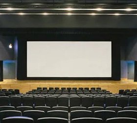 Large-format curved projection screen installed in an auditorium with tiered seating
